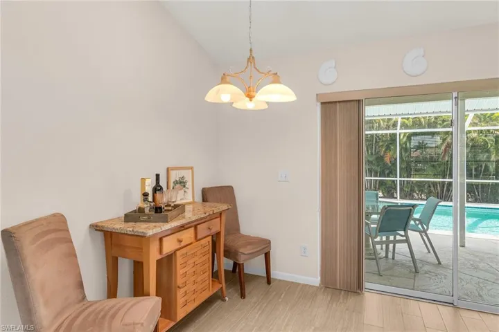 Sitting room with lofted ceiling, baseboards, a chandelier, and light wood-type flooring