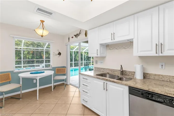 Kitchen with stainless steel dishwasher, a sink, white cabinets, and visible vents