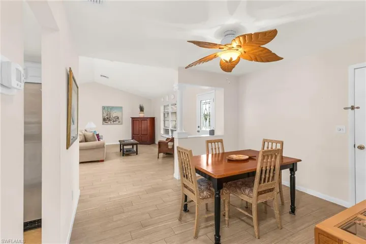 Dining area with a ceiling fan, baseboards, lofted ceiling, and light wood-style floors
