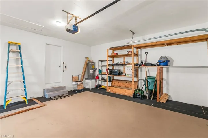 Garage featuring a garage door opener and electric water heater