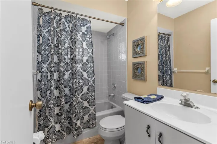 Bathroom featuring shower / bathtub combination with curtain, vanity, and toilet