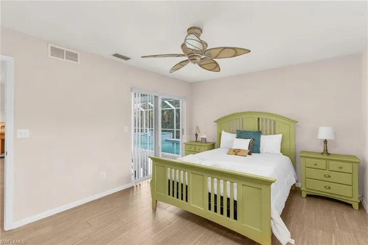 Bedroom with wood finished floors, visible vents, a ceiling fan, and access to outside