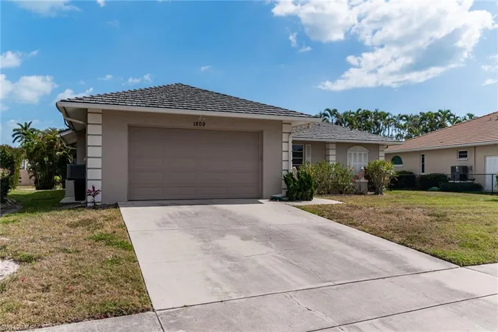 Ranch-style house featuring a front lawn, an attached garage, concrete driveway, and stucco siding