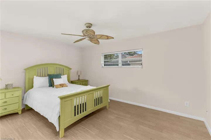 Bedroom featuring a ceiling fan, light wood finished floors, and baseboards