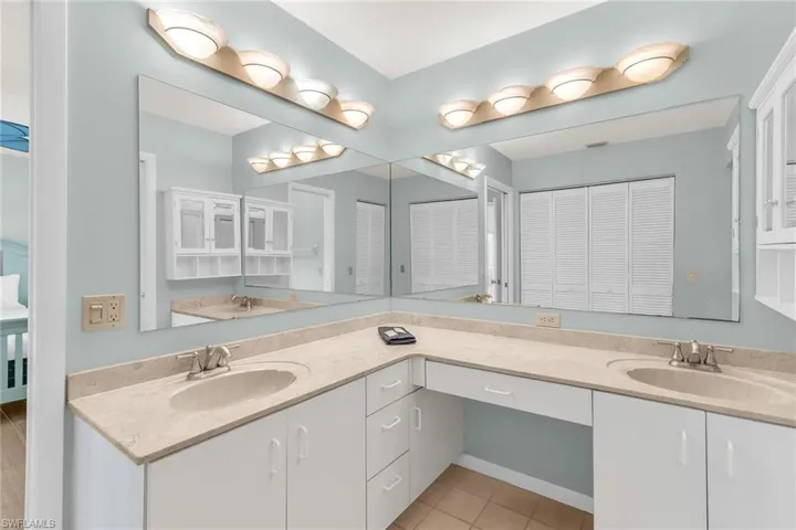 Bathroom with a closet, tile patterned flooring, double vanity, and a sink