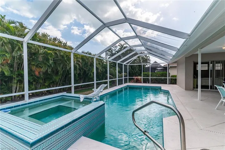 View of pool with a patio, glass enclosure, and a pool with connected hot tub