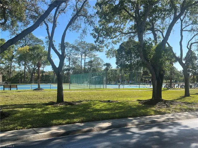 View of property's community with a water view, a yard, and tennis court