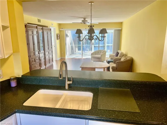 Kitchen featuring white cabinetry, a chandelier, and sink