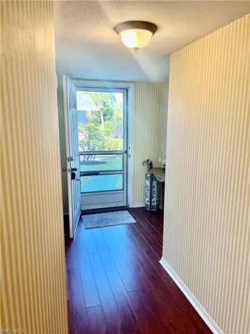 Doorway to outside with dark hardwood / wood-style flooring and a textured ceiling