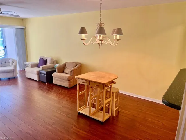 Dining room with dark hardwood / wood-style flooring and ceiling fan with notable chandelier