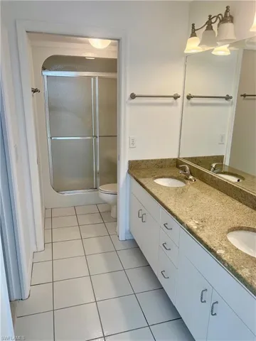 Bathroom with tile patterned floors, toilet, a shower with door, and vanity