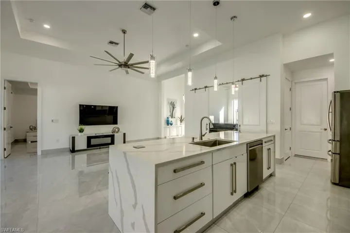 Kitchen featuring white cabinetry, sink, a kitchen island with sink, a tray ceiling, and stainless steel appliances