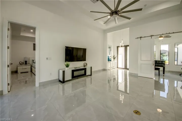 Living room with ceiling fan, a barn door, and a raised ceiling