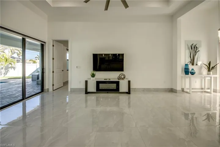 Unfurnished living room featuring ceiling fan, a towering ceiling, and a raised ceiling