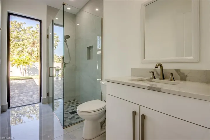 Bathroom with a shower with door, vanity, tile patterned flooring, and toilet