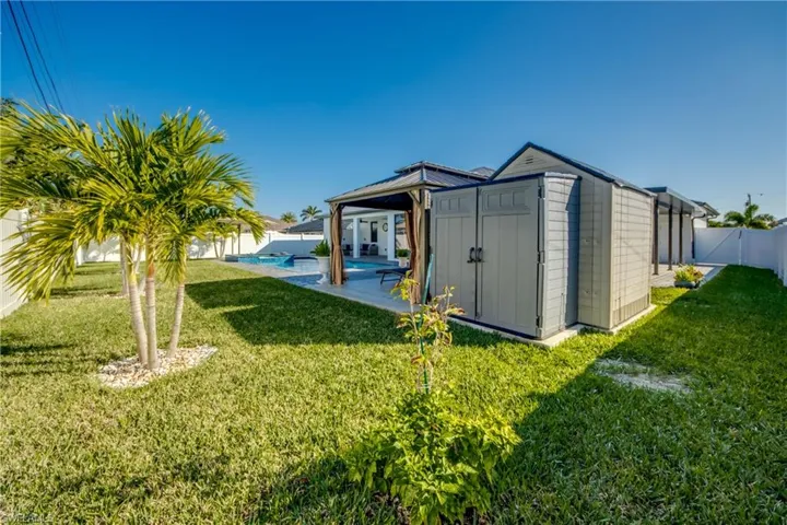 View of outdoor structure with a fenced in pool and a lawn