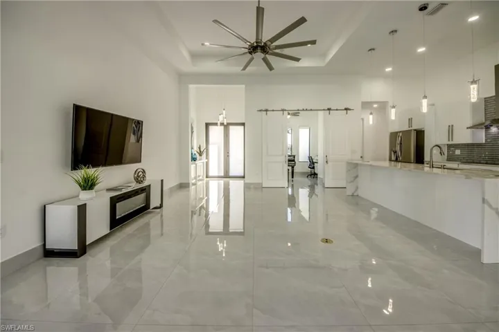 Living room with sink, a raised ceiling, ceiling fan, a barn door, and a high ceiling