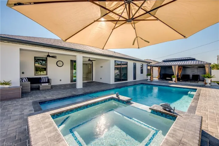 View of pool featuring ceiling fan, a gazebo, an outdoor living space, a patio area, and an in ground hot tub