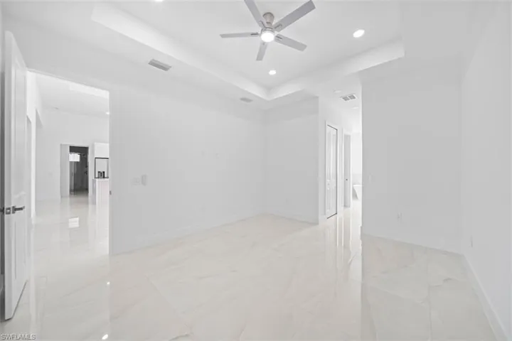 Spacious room featuring large format tile flooring, a tray ceiling, recessed lighting, and a contemporary ceiling fan