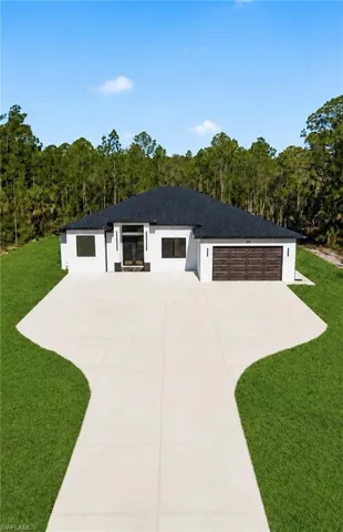 Contemporary exterior featuring a split-level roofline, white stucco finish, and a wood-finish garage door