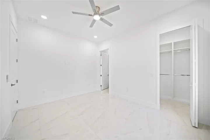 Spacious room with light-toned tile flooring, recessed lighting, and a modern ceiling fan