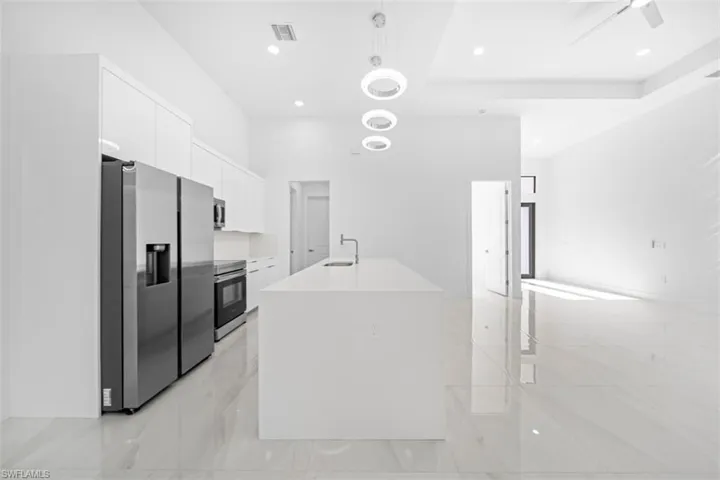 Modern kitchen featuring a large center island, stainless steel appliances, recessed lighting, and contemporary pendant fixtures