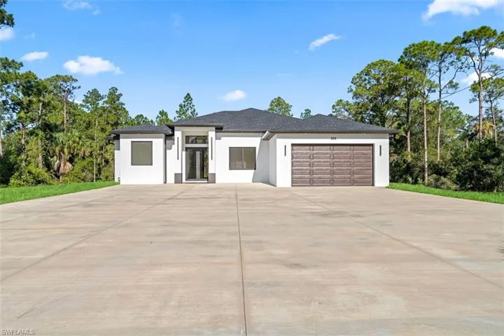 Contemporary residence featuring a white stucco exterior, dark shingle roof, and an expansive concrete driveway