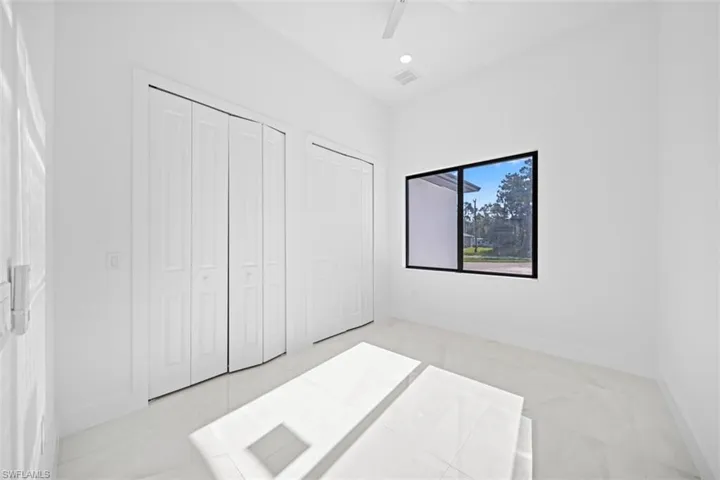 Interior room featuring white walls, large format tile flooring, and a black-framed window