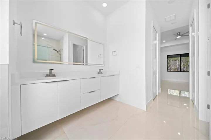 Modern bathroom vanity with dual undermount sinks, white cabinetry, and a light-strip mirror