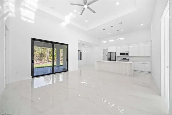 Expansive open-concept living area featuring high vaulted ceilings, polished tile flooring, and a modern kitchen