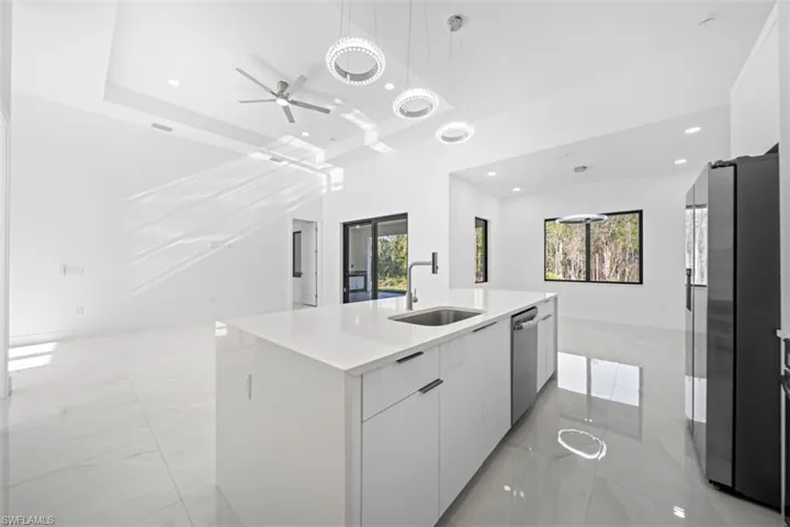 Modern kitchen island with integrated sink and dishwasher, pristine white cabinetry, and a light-toned countertop