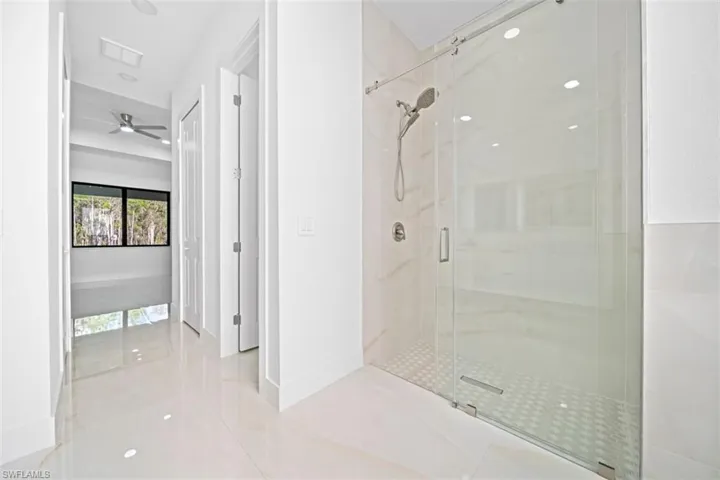 Spacious hallway with polished tile flooring leading to a modern glass-enclosed shower