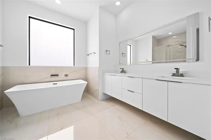 Soaking tub with wall-mounted fixtures, set against a large window