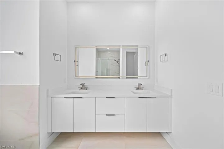 Double vanity with white cabinetry, integrated sinks, chrome fixtures, and a white countertop