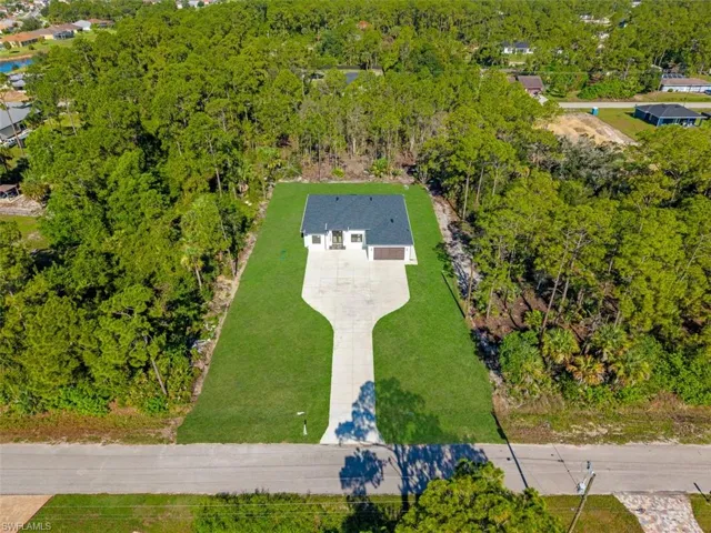 White exterior with dark roof and attached garage, set on a manicured lawn