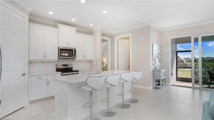 Kitchen featuring sink, stainless steel appliances, an island with sink, and white cabinets