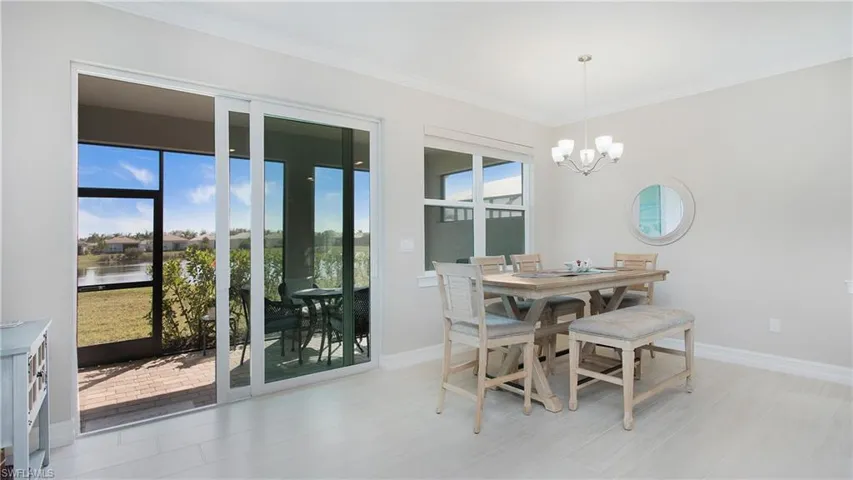 Dining area featuring a notable chandelier, a water view, crown molding, and light hardwood / wood-style flooring