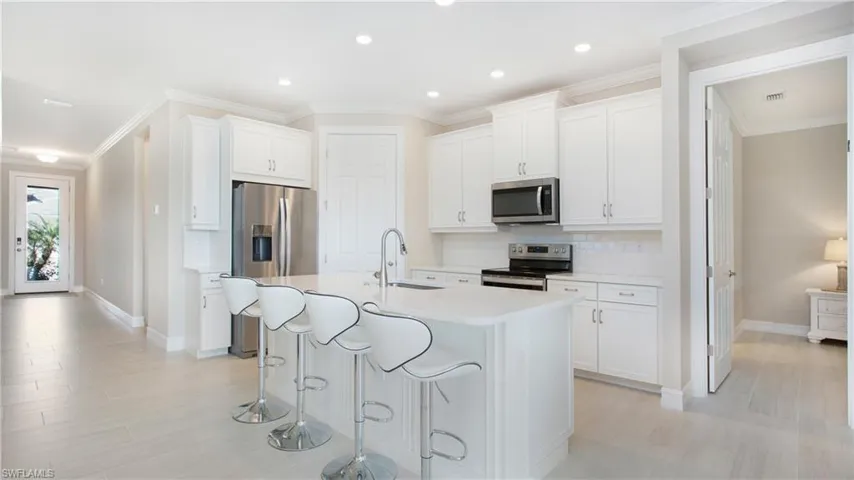 Kitchen featuring white cabinets, appliances with stainless steel finishes, sink, and a kitchen island with sink