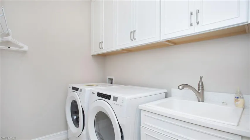 Laundry area featuring sink, separate washer and dryer, and cabinets