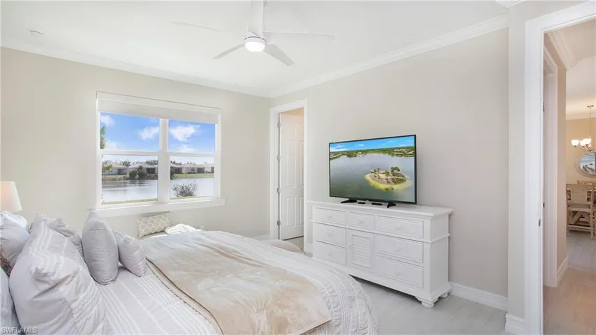 Main bedroom with ceiling fan with notable chandelier and crown molding