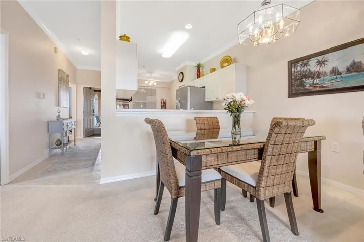 Dining room featuring light carpet, baseboards, and crown molding