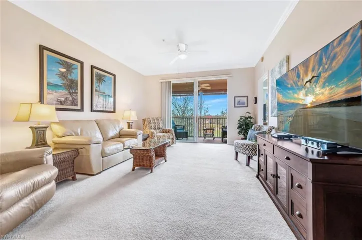 Carpeted living room with a ceiling fan and crown molding