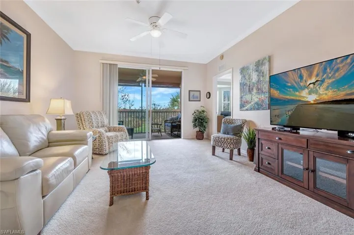 Carpeted living area with visible vents, ornamental molding, and a ceiling fan
