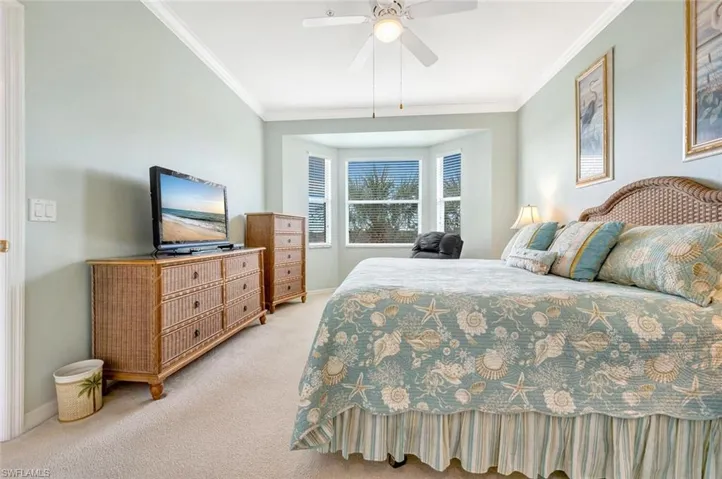 Bedroom with a ceiling fan, light carpet, crown molding, and baseboards