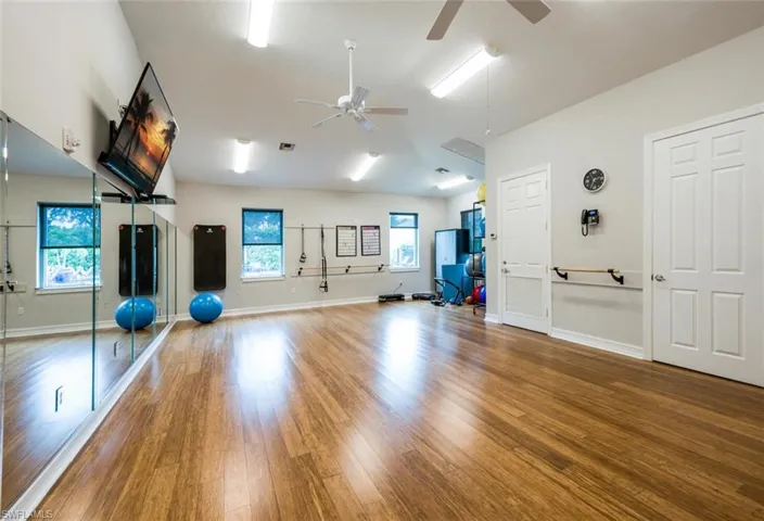 Exercise room featuring visible vents, baseboards, and wood finished floors