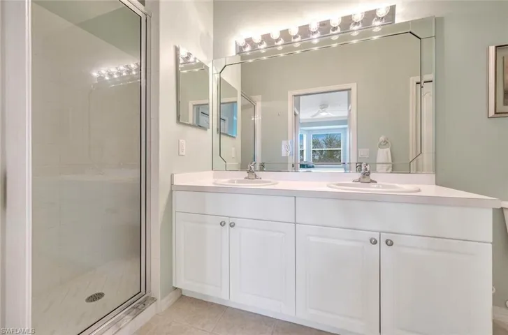 Bathroom with double vanity, a shower stall, a sink, and tile patterned floors