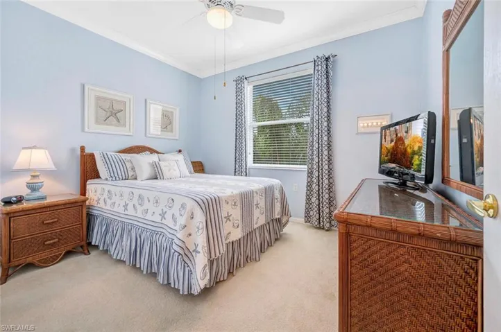 Bedroom featuring light carpet, ornamental molding, and a ceiling fan