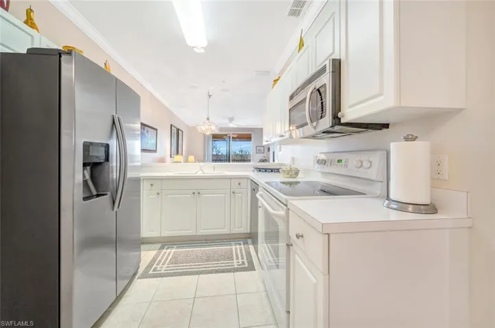 Kitchen with visible vents, appliances with stainless steel finishes, ornamental molding, a sink, and a peninsula