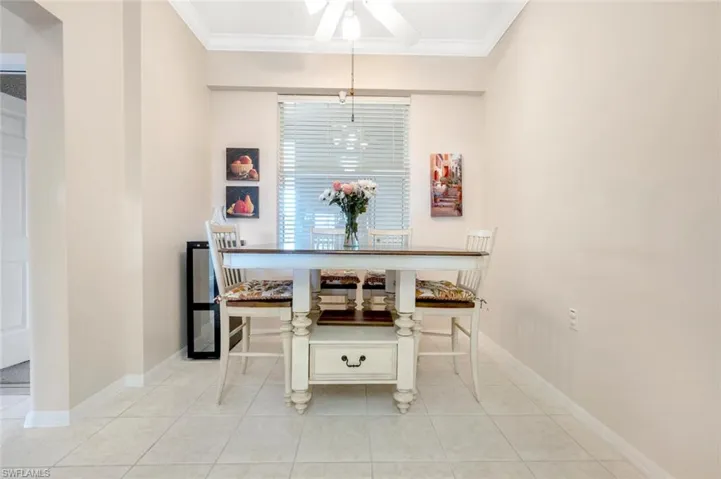 Dining room featuring light tile patterned floors, ornamental molding, a ceiling fan, and baseboards