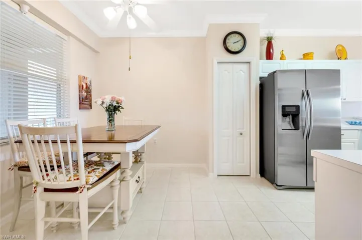 Kitchen featuring crown molding, stainless steel fridge with ice dispenser, light countertops, light tile patterned flooring, and baseboards